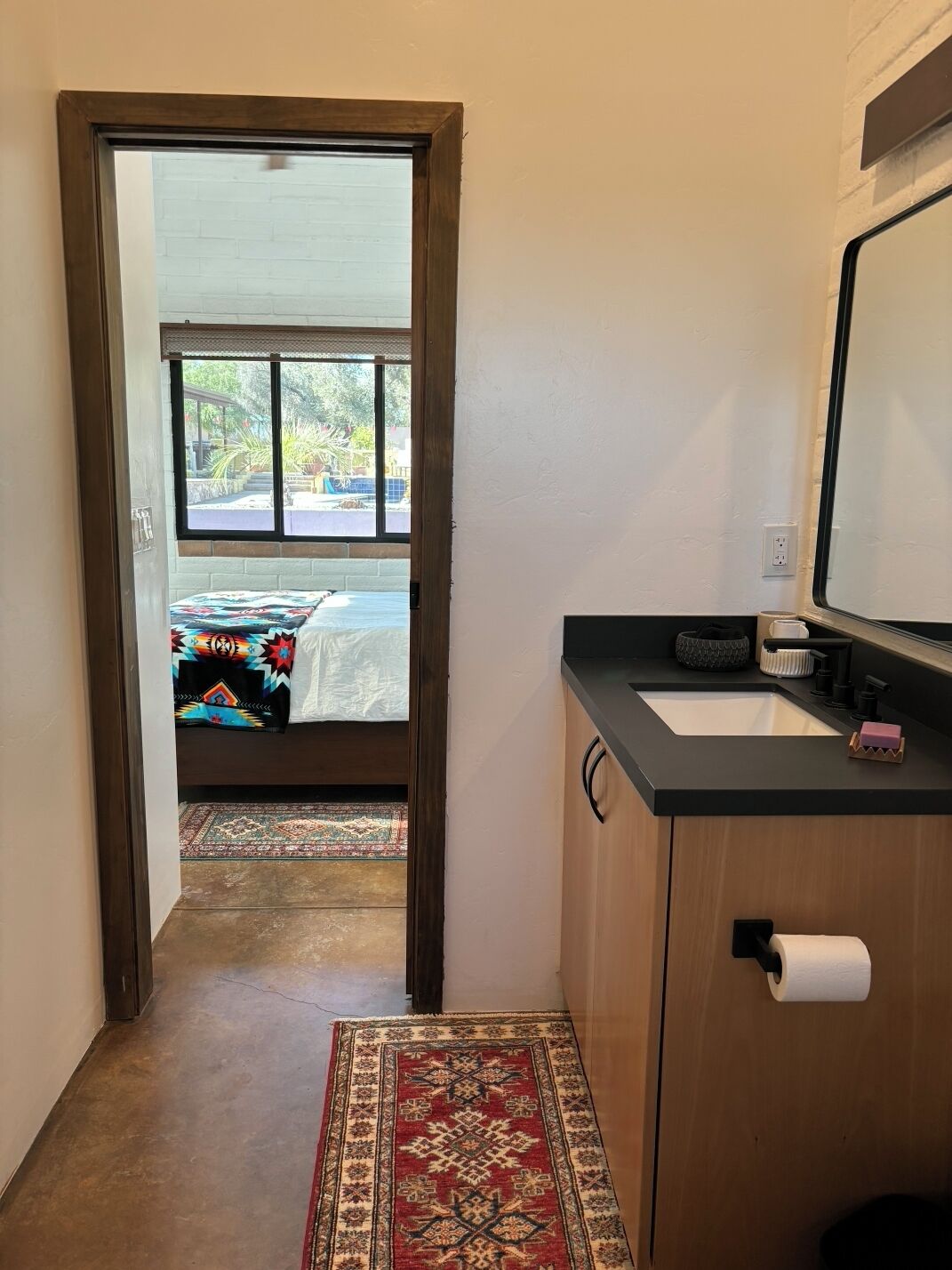A bathroom with a sink, mirror, and toilet paper holder.