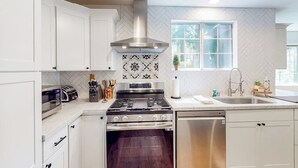 Een moderne keuken met witte kastjes, een roestvrijstalen fornuis en een vaatwasser.