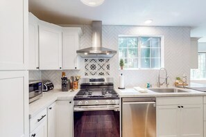 A modern kitchen with white cabinetry, a stainless steel range, and a dishwasher. - Walk to lake  | BBQ Grill | Fire pit| Shuffleboard (Crestline)