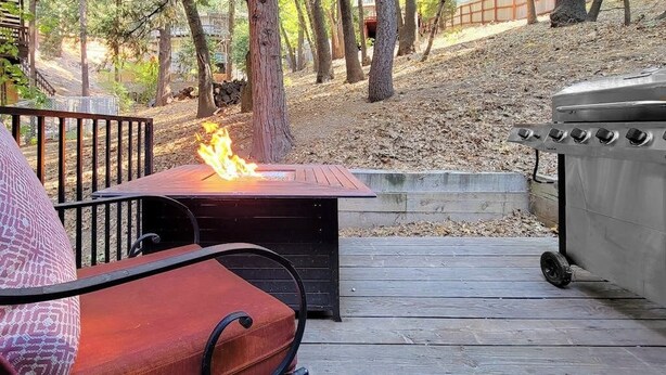 Een terras met een vuurplaats, een barbecue en een bank.
