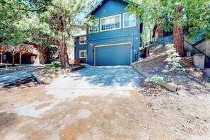 A two-story building with a garage, surrounded by trees and a dirt driveway. - Walk to lake  | BBQ Grill | Fire pit| Shuffleboard (Crestline)