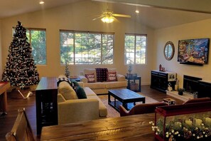 A living room with a large Christmas tree, a sofa, a coffee table, and a fireplace. - Walk to lake  | BBQ Grill | Fire pit| Shuffleboard (Crestline)