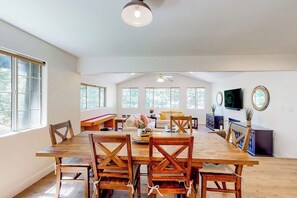 A spacious living room with a large wooden dining table, multiple chairs, a sofa, and a television. - Walk to lake  | BBQ Grill | Fire pit| Shuffleboard (Crestline)