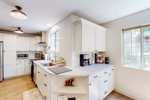 A modern kitchen with white cabinetry, a built-in microwave, and a coffee station. - Walk to lake  | BBQ Grill | Fire pit| Shuffleboard (Crestline)