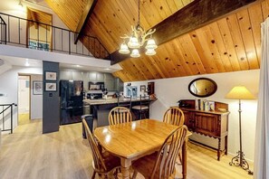 A spacious loft-style room with a dining area, kitchen, and a mezzanine level. - Enchanting lake retreat with fireplace, games, & great deck views - dog-friendly (Crestline)