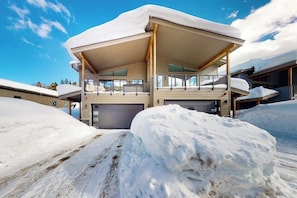 Ein modernes Gebäude mit überdachter Außenfläche, einer Garage und Schneebedeckung.