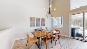 Ein Essbereich mit einem Holztisch, Stühlen, einer Chandelierleuchtre und Kunstwerken an der Wand.