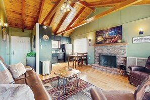 Ein gemütliches Wohnzimmer mit Kamin, Holzbalkendecke und Essbereich.