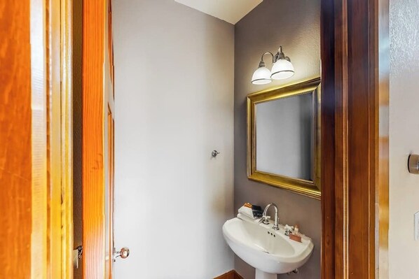 A bathroom with a white sink, a mirror with a gold frame, and a light fixture above the mirror. - Exclusive Water Dance home with fireplace & deck - Walk to marina & Main St (Frisco)