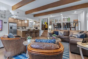 Eine moderne Küche mit Holzschränken, einem Edelstahlkühlschrank und einem Essbereich mit Korbmöbeln und einem Couchtisch.