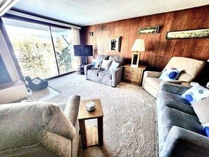 Ein Wohnzimmer mit einer Couch, Sesseln, einem Couchtisch und einem Fernseher.
