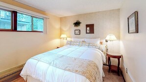 Un dormitorio con una cama, dos mesitas de noche, una ventana y lámparas de pared.
