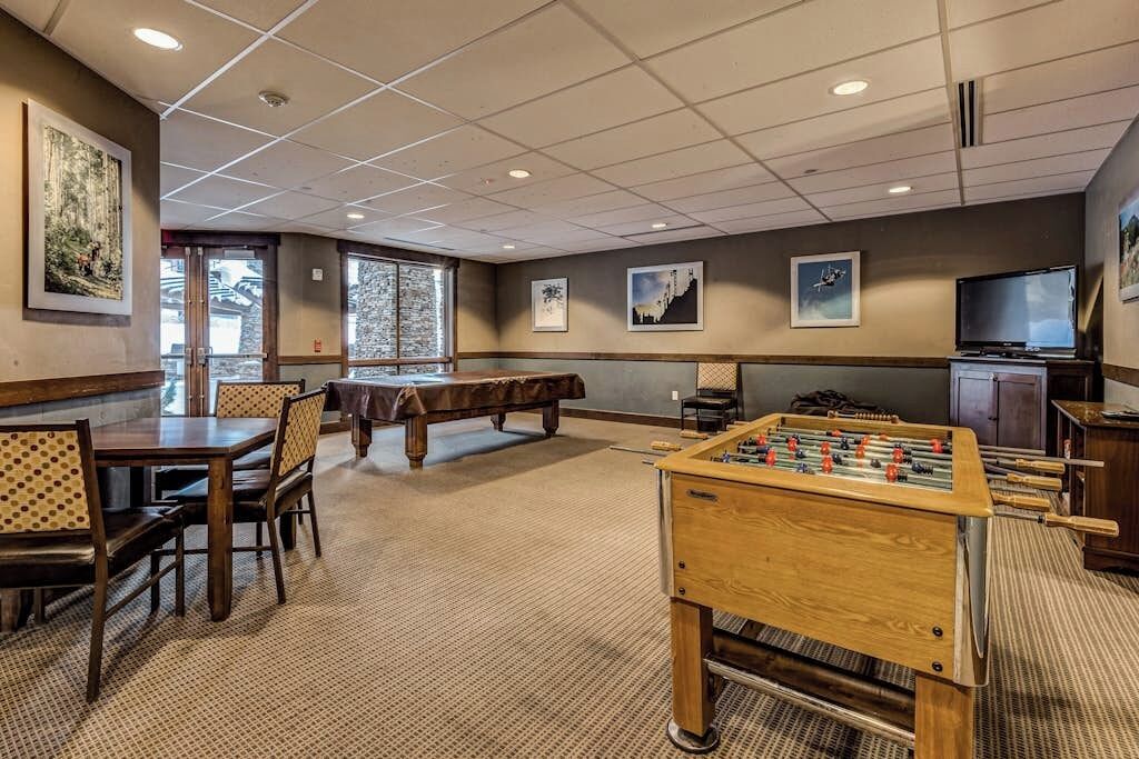 Een kamer met een pooltafel, een tafelvoetbalspel en een televisie.