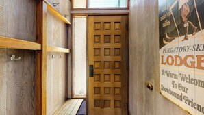 Una puerta de madera con un diseño de cuadrícula, un banco de madera y un cartel con texto.