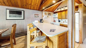 Una cocina con armarios de madera, encimera blanca y comedor con sillas de madera.
