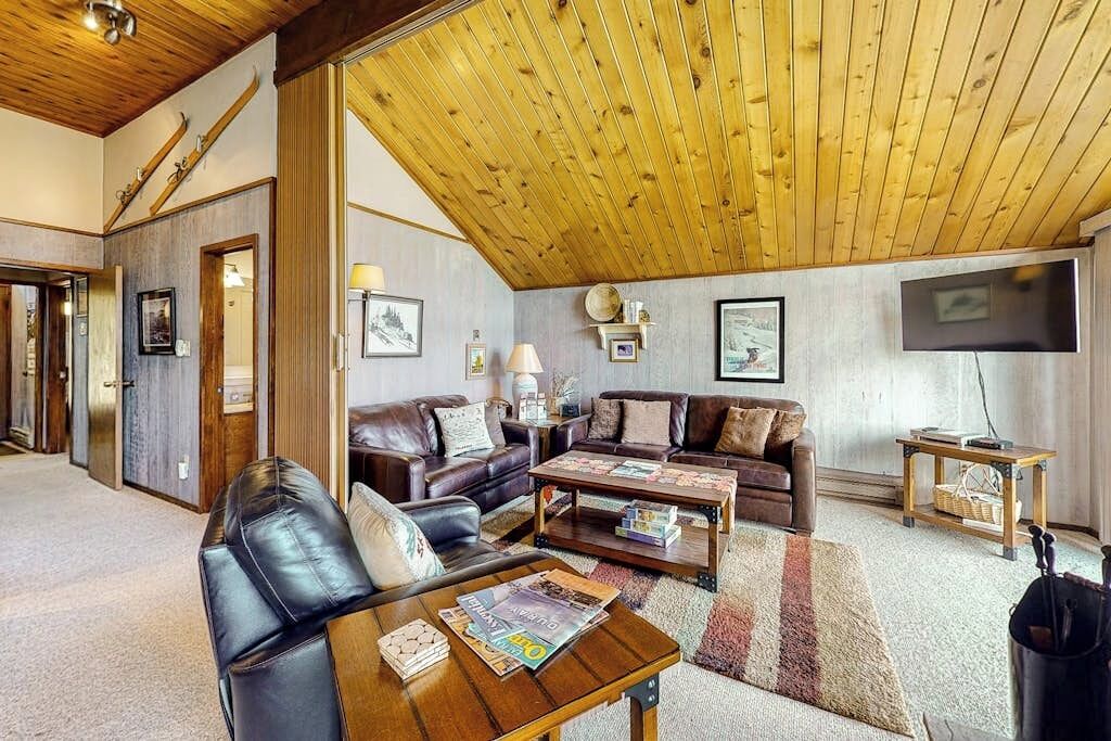 A spacious living room with leather sofas, a wooden coffee table, and a television.