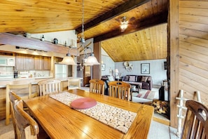 A spacious kitchen with wooden cabinets, a dining table with chairs, and a living area with a couch and fireplace. - Ski-in/ski-out gem - top-floor condo - lake & mountain views, fireplace (Durango)