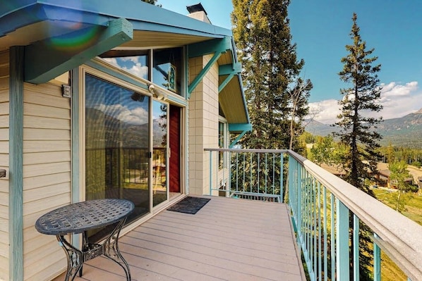 A wooden deck with a table, a glass door, and a view of trees and mountains. - Ski-in/ski-out gem - top-floor condo - lake & mountain views, fireplace (Durango)