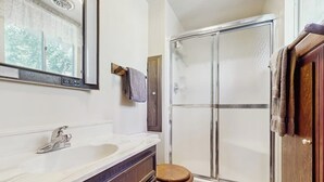 A bathroom with a shower, a sink, a toilet, and a mirror. - Rustic, wooded escape near the village w/ a lovely deck (Lake Arrowhead)