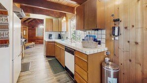 A kitchen with wooden cabinets, a white countertop, and a stainless steel trash can. - Rustic, wooded escape near the village w/ a lovely deck (Lake Arrowhead)