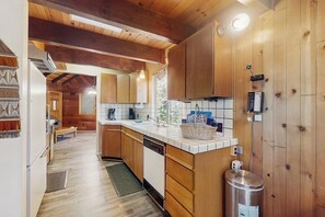 A kitchen with wooden cabinets, a white countertop, and a stainless steel trash can. - Rustic, wooded escape near the village w/ a lovely deck (Lake Arrowhead)