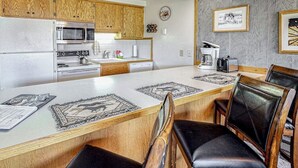 Eine Küche mit Holzausstattung, einer Mikrowelle, einem Backofen, einer Kaffeemaschine und einem Essbereich mit Tisch und Stühlen.