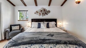 A bedroom with a bed, bedside tables, a chair, a window, and a wall art piece. - Dog-friendly retreat with fast WiFi, washer/dryer & wood-burning fireplace (Running Springs)