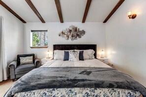 A bedroom with a bed, bedside tables, a chair, a window, and a wall art piece. - Dog-friendly retreat with fast WiFi, washer/dryer & wood-burning fireplace (Running Springs)