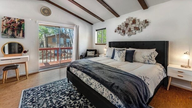 A bedroom with a bed, a desk, a chair, a rug, a window, and a balcony. - Dog-friendly retreat with fast WiFi, washer/dryer & wood-burning fireplace (Running Springs)