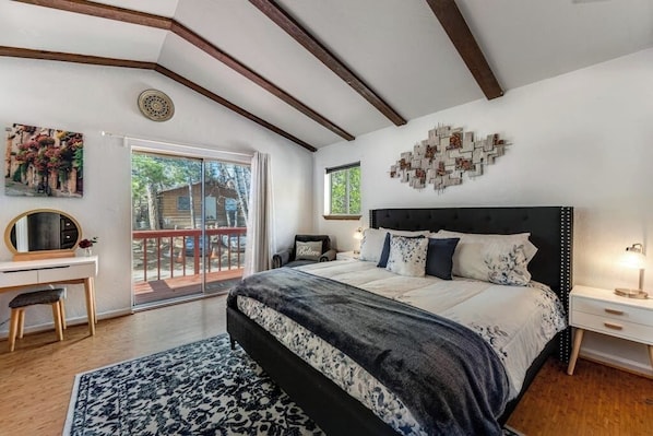 A bedroom with a bed, a desk, a chair, a rug, a window, and a balcony. - Dog-friendly retreat with fast WiFi, washer/dryer & wood-burning fireplace (Running Springs)