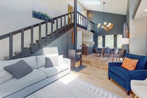 Ein modernes Wohnzimmer mit Treppe, Essbereich und Küche.