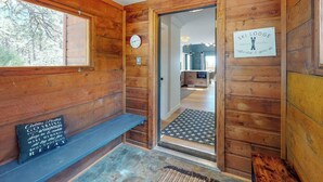 Interno di una baita in legno con una panca, un orologio e un cartello che indica che si tratta di un rifugio per sci.