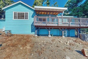 Ein blaues Haus mit einer Holzterrasse und einem überdachten Bereich.