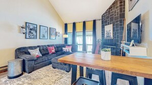 Una sala moderna con un sofá seccional, una mesa de comedor de madera y una cocina con salpicadero de azulejos.