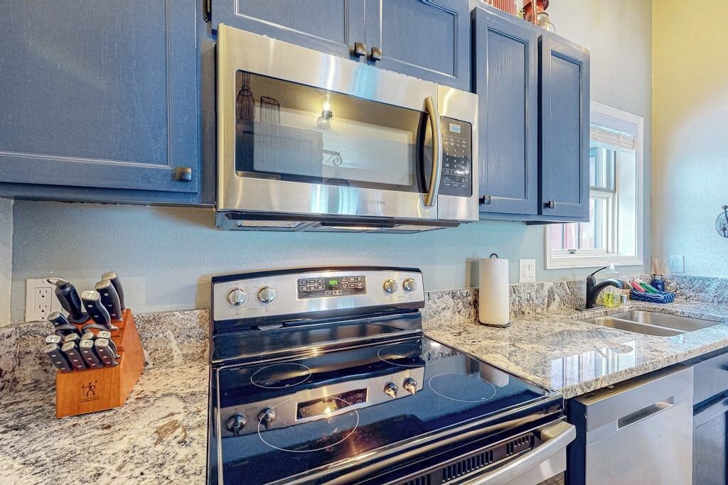 A kitchen with a stainless steel microwave, oven, and granite countertop.