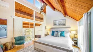 A bedroom with a large bed, a wooden ceiling, a balcony, and a view of trees. - Modern alpine escape with two decks, grill, private sauna, fireplace (Lake Arrowhead)