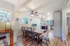 Une cuisine spacieuse avec un coin repas, de grandes fenêtres et un ventilateur de plafond.