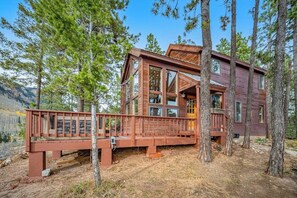 A cabin with a deck, surrounded by trees, with a clear view of the mountains in the background. - Delightful mountain retreat, NEW private hot tub, fireplace, deck, & great views (Durango)