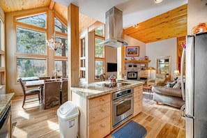 A spacious kitchen with large windows, a dining area, and a living room with a fireplace. - Delightful mountain retreat, NEW private hot tub, fireplace, deck, & great views (Durango)