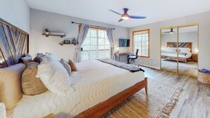 A bedroom with a bed, a desk, a chair, a ceiling fan, and a large mirror. - Spacious home with three decks, views, game room, fireplace, & fast WiFi (Lake Arrowhead)