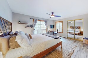 A bedroom with a bed, a desk, a chair, a ceiling fan, and a large mirror. - Spacious home with three decks, views, game room, fireplace, & fast WiFi (Lake Arrowhead)