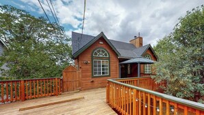 A wooden cabin with a deck, a chimney, and a large window. - Spacious home with three decks, views, game room, fireplace, & fast WiFi (Lake Arrowhead)