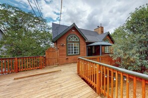 A wooden cabin with a deck, a chimney, and a large window. - Spacious home with three decks, views, game room, fireplace, & fast WiFi (Lake Arrowhead)