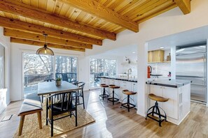 Eine moderne Küche mit Holzboden, großen Fenstern und einer zentralen Kochinsel mit Hockern.