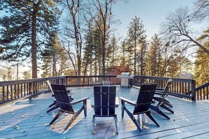 Eine Terrasse mit Sitzgelegenheiten und Grill, umgeben von hohen Bäumen.