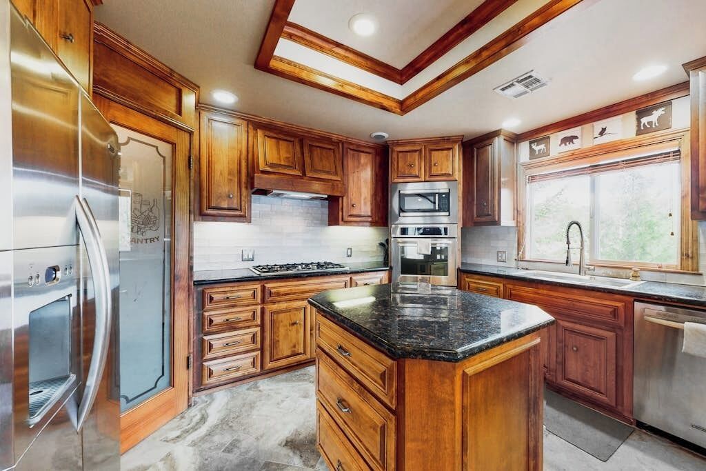 Una cocina con armarios de madera, electrodomésticos de acero inoxidable y una isla grande.