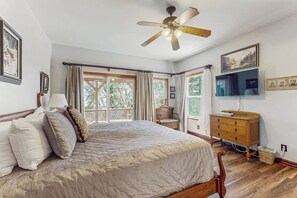 Ein Schlafzimmer mit einem Bett, einem Holzschrank, einem Deckenventilator und einem an der Wand befestigten Fernseher.