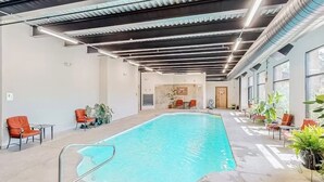 Ein Innenpool mit Betonboden, Metallgeländern und orangefarbenen Stühlen rundum.