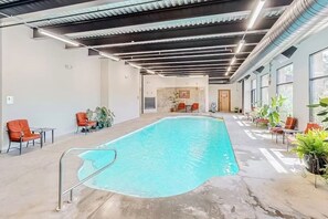 An indoor swimming pool with a concrete floor, metal railings, and orange chairs around the perimeter. - Spacious Condo at Tamarron, Pool/Hot Tub/Workout Access, Golf/Tennis On Site (Durango)