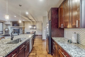 A kitchen with granite countertops, wooden cabinets, a stainless steel refrigerator, and pendant lighting. - Beautiful townhome w/ balcony, hot tub & mountain views. Close to slopes (Keystone)
